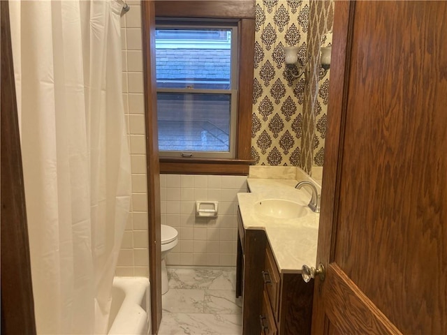 bathroom featuring marble finish floor, tile walls, toilet, vanity, and wallpapered walls