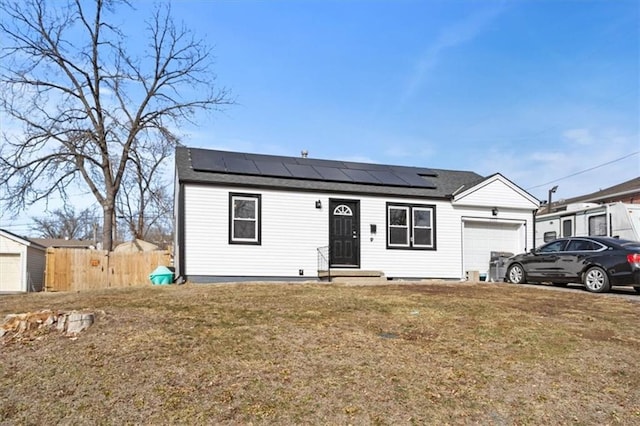 single story home featuring an attached garage, fence, a front lawn, and solar panels