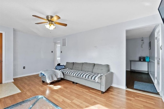 living room featuring baseboards, visible vents, ceiling fan, and light wood finished floors