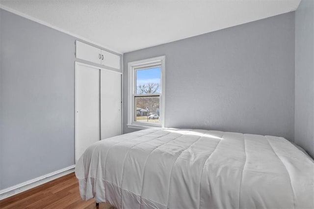 bedroom with a closet, wood finished floors, and baseboards