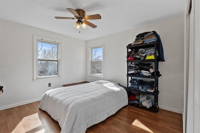 bedroom featuring dark wood-style flooring, a ceiling fan, and baseboards