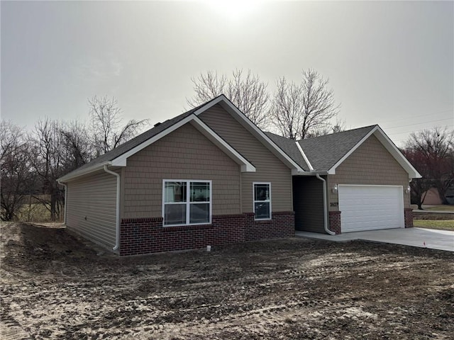 view of front of home featuring driveway, brick siding, and an attached garage