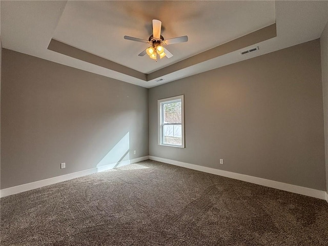 unfurnished room featuring visible vents, ceiling fan, baseboards, a tray ceiling, and carpet floors