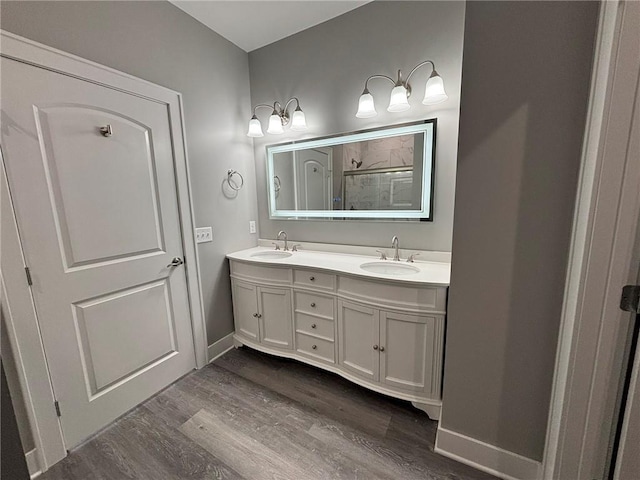 full bathroom with double vanity, wood finished floors, a stall shower, and a sink