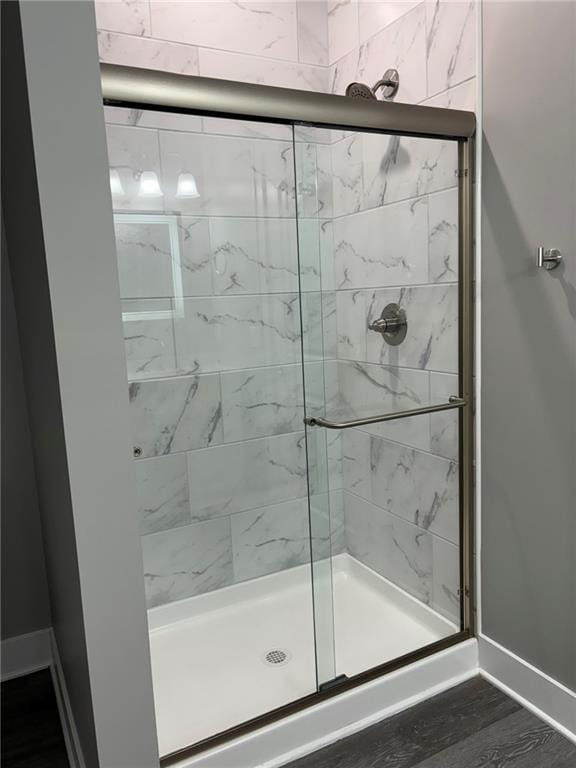 full bath featuring a shower stall, wood finished floors, and baseboards