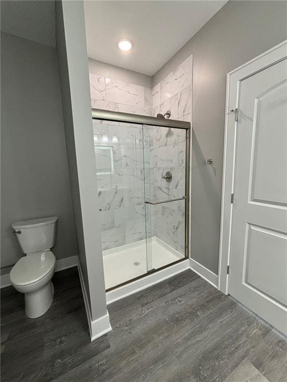 bathroom featuring wood finished floors, a stall shower, and baseboards