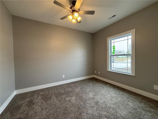 spare room with dark colored carpet, visible vents, baseboards, and ceiling fan