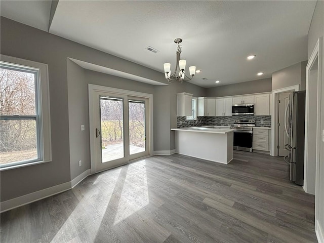 kitchen featuring visible vents, a notable chandelier, stainless steel appliances, decorative backsplash, and dark wood-style flooring