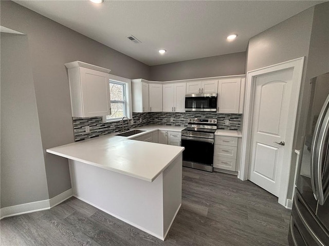 kitchen with visible vents, dark wood-type flooring, a sink, tasteful backsplash, and stainless steel appliances