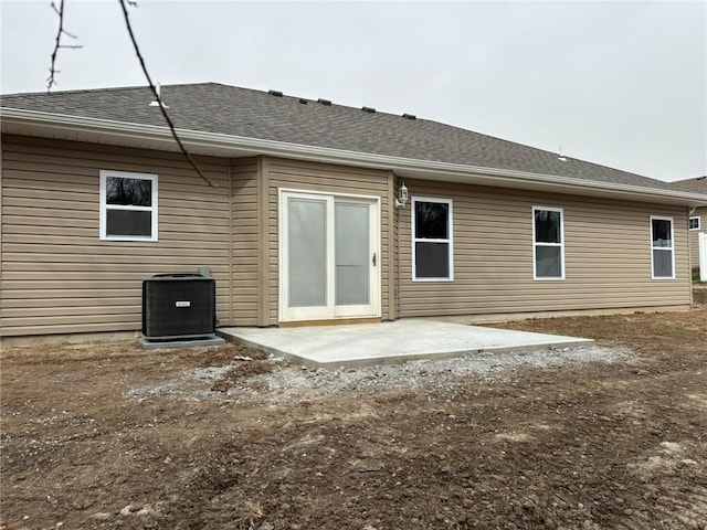 back of house with central air condition unit, a patio, and roof with shingles