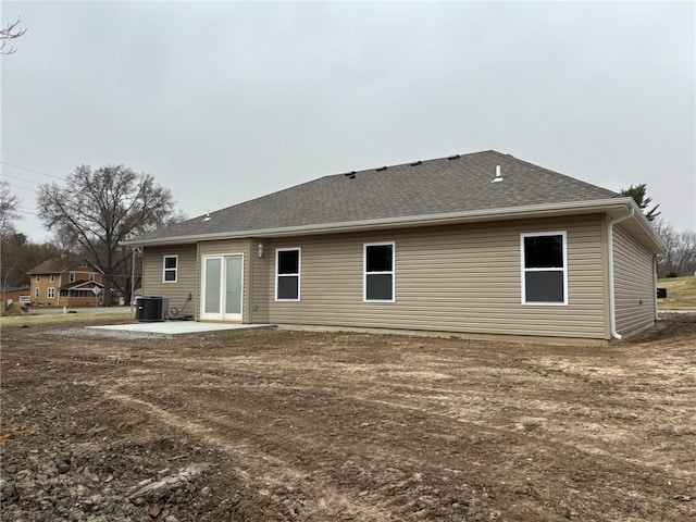 back of property with cooling unit, a patio, and roof with shingles