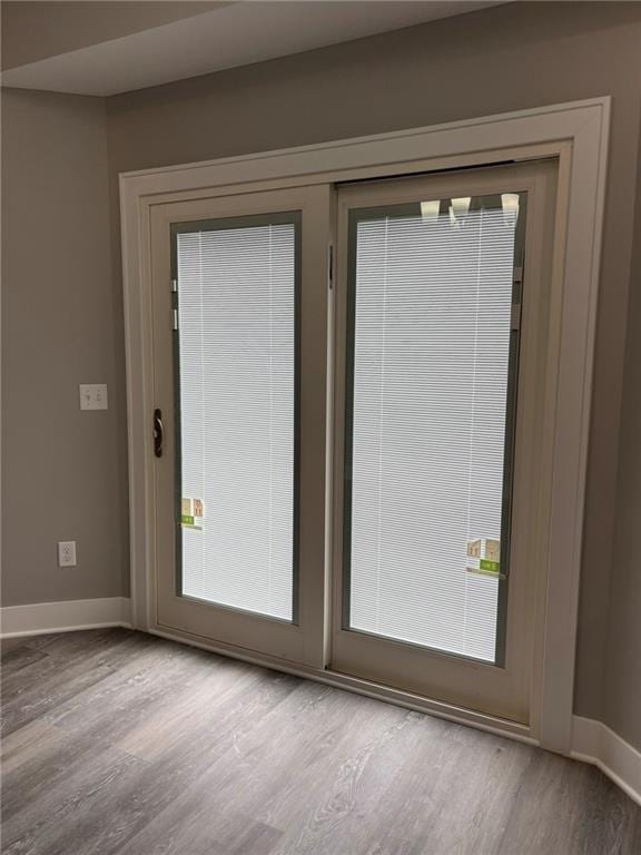 doorway with wood finished floors and baseboards