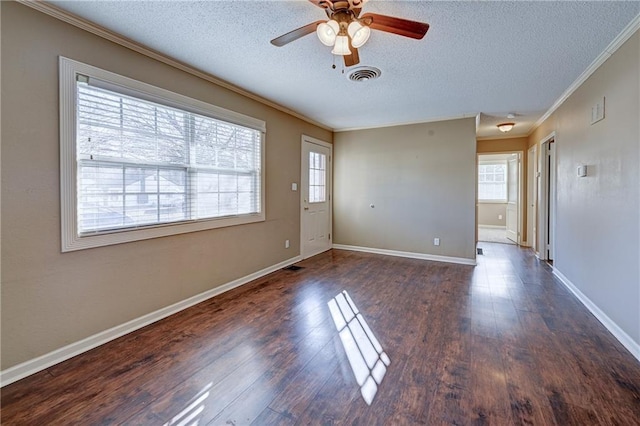 interior space with visible vents, dark wood-type flooring, ornamental molding, a textured ceiling, and baseboards