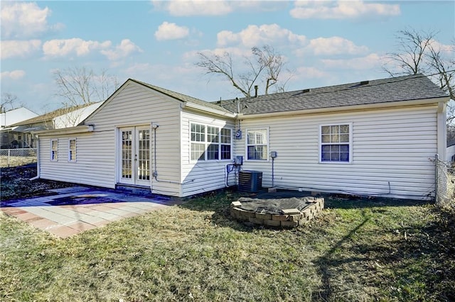 back of property with french doors, a lawn, an outdoor fire pit, fence, and cooling unit