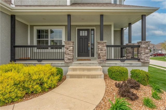 entrance to property with a porch, stucco siding, and stone siding