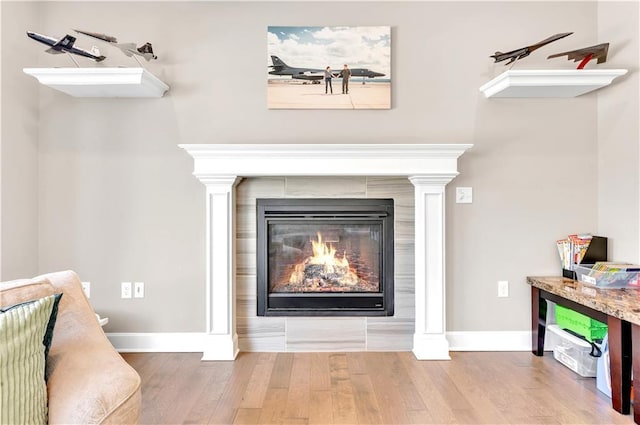 details featuring baseboards, ornate columns, wood finished floors, and a tile fireplace