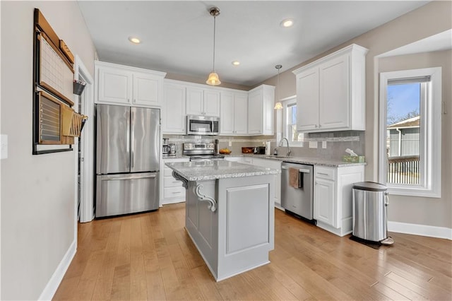 kitchen with a sink, appliances with stainless steel finishes, white cabinets, and decorative backsplash