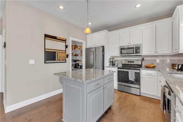 kitchen featuring stainless steel appliances, white cabinetry, light wood finished floors, and a center island