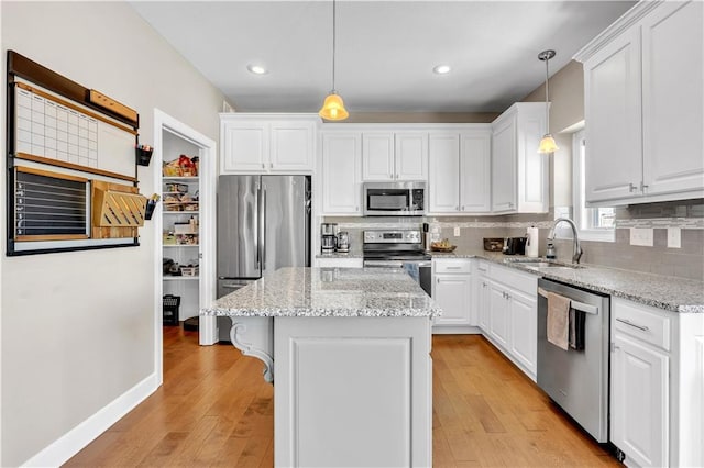 kitchen featuring a sink, a center island, stainless steel appliances, white cabinetry, and decorative backsplash