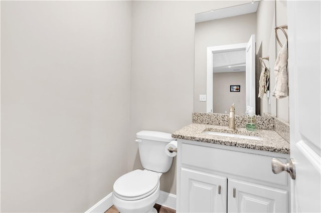 bathroom featuring toilet, baseboards, and vanity