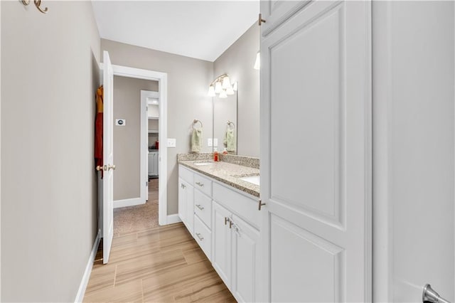 full bathroom with baseboards, double vanity, and a sink