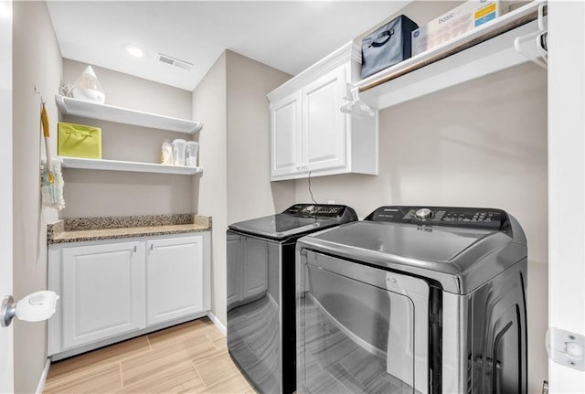 laundry room featuring baseboards, visible vents, cabinet space, and washer and dryer