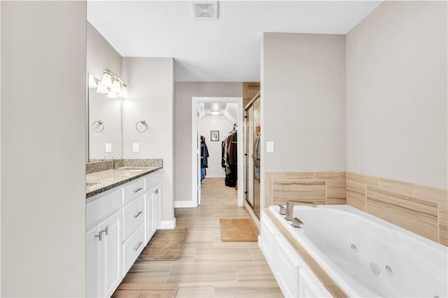 bathroom with visible vents, a shower stall, vanity, baseboards, and a whirlpool tub