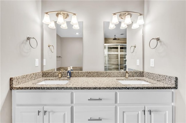 full bath with a sink, a shower with door, and double vanity