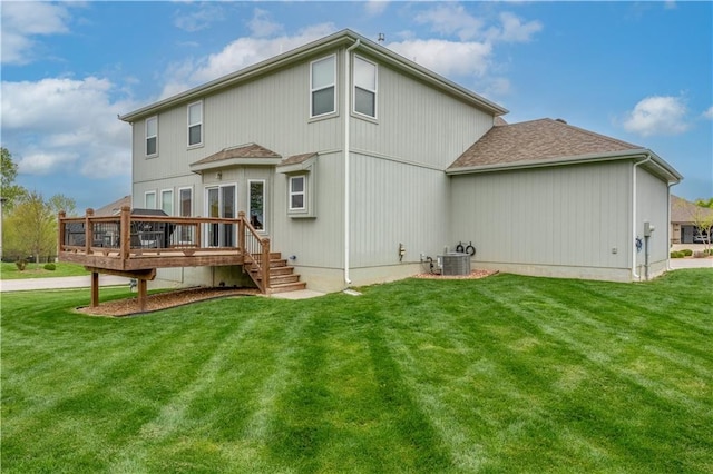 rear view of property featuring a lawn, a wooden deck, and a shingled roof