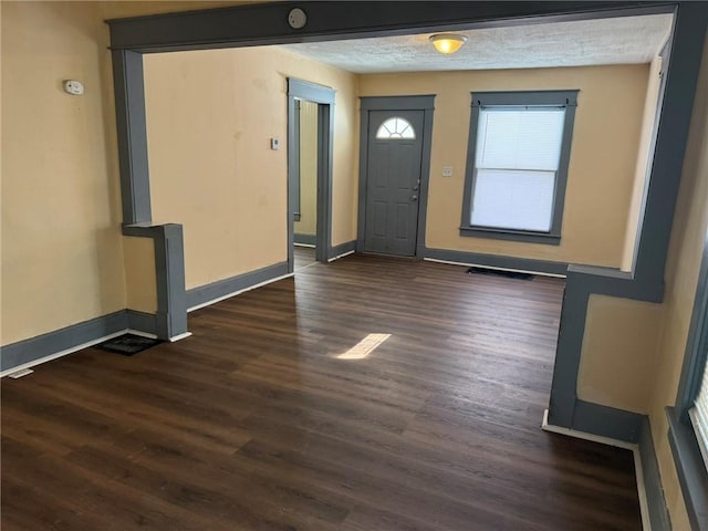 foyer entrance featuring dark wood-style flooring, visible vents, a textured ceiling, and baseboards