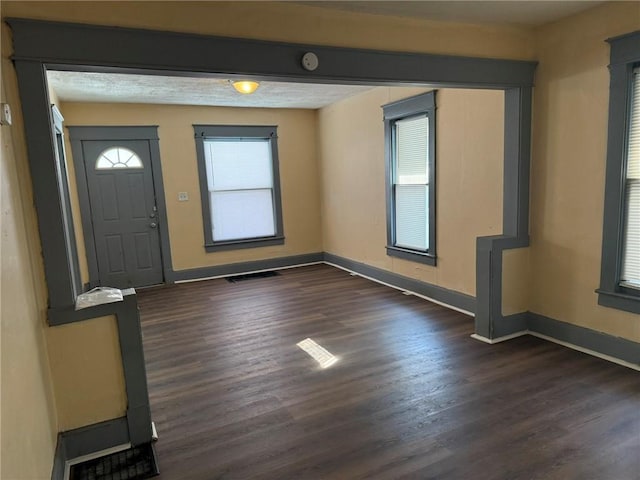 foyer featuring dark wood finished floors, visible vents, and baseboards