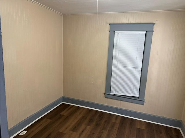 spare room with baseboards and dark wood-type flooring