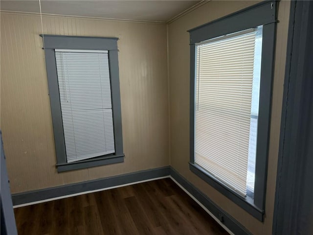 unfurnished room with dark wood-style flooring, a healthy amount of sunlight, crown molding, and baseboards