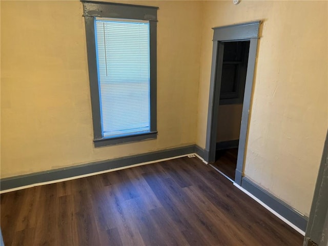 spare room featuring dark wood-style flooring and baseboards