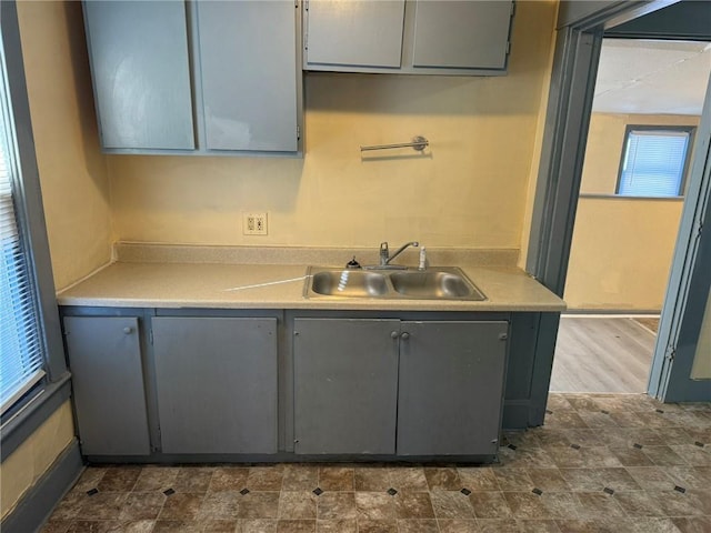 kitchen featuring light countertops, a sink, and gray cabinetry