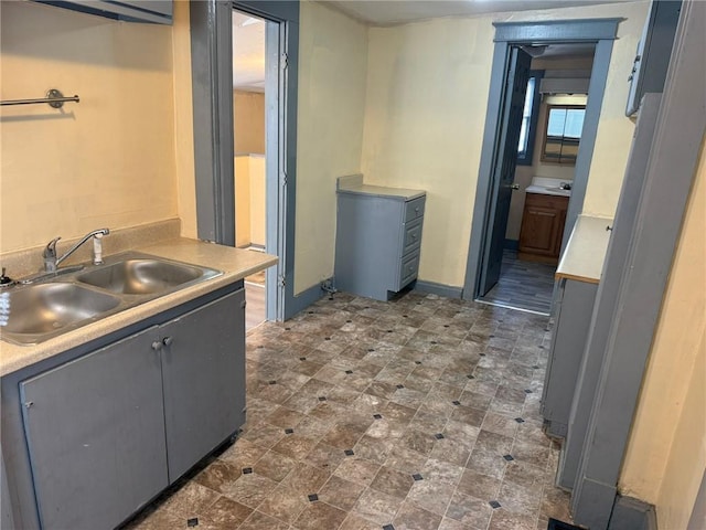 kitchen with light countertops, gray cabinets, and a sink