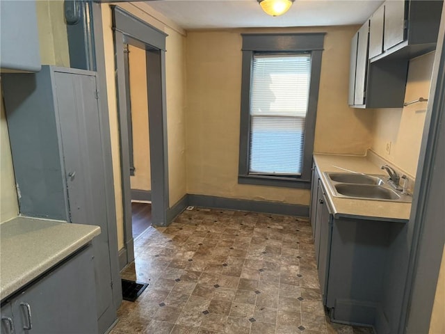 kitchen with light countertops, a sink, and baseboards