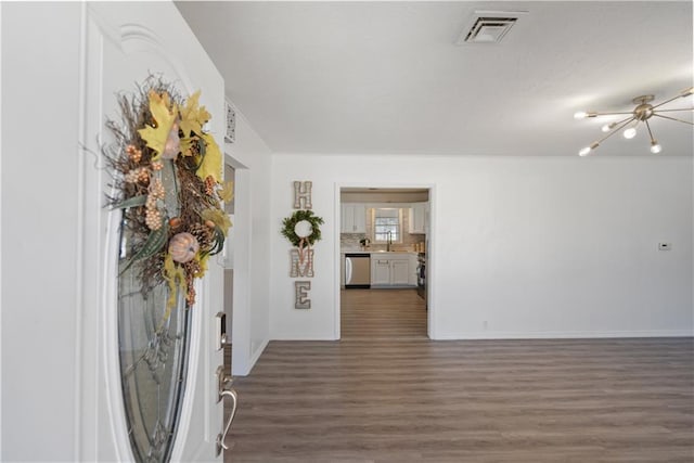 foyer featuring dark wood-type flooring, a chandelier, visible vents, and baseboards