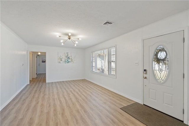 foyer featuring a textured ceiling, light wood finished floors, visible vents, and baseboards