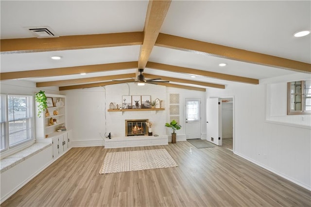 unfurnished living room with visible vents, baseboards, ceiling fan, wood finished floors, and a brick fireplace