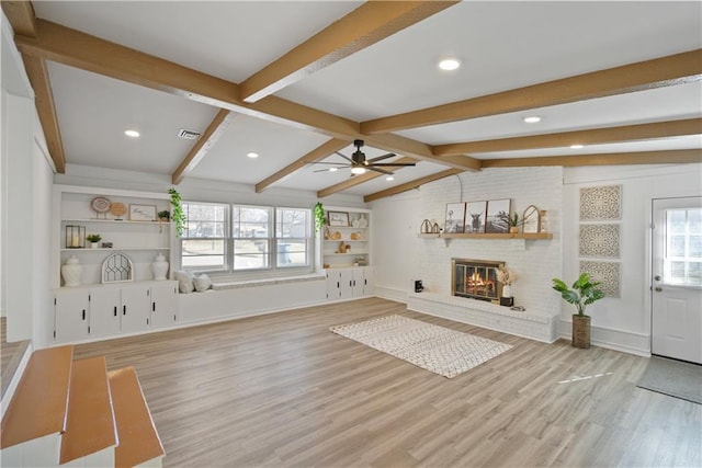 unfurnished living room featuring light wood finished floors, visible vents, built in features, lofted ceiling with beams, and a fireplace