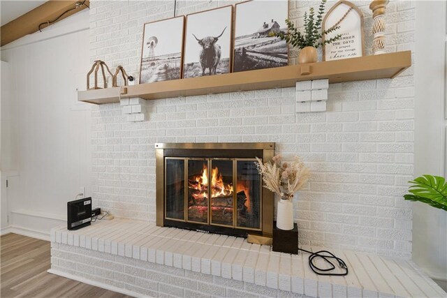 details with a brick fireplace and wood finished floors