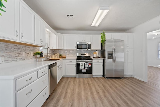 kitchen with light countertops, visible vents, appliances with stainless steel finishes, white cabinets, and a sink