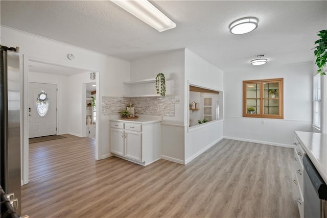 kitchen with light wood finished floors, open shelves, light countertops, appliances with stainless steel finishes, and white cabinets