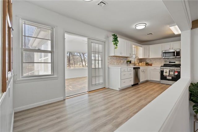 kitchen with light countertops, visible vents, appliances with stainless steel finishes, white cabinets, and a sink