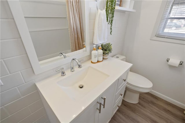 bathroom with toilet, baseboards, wood finished floors, and vanity