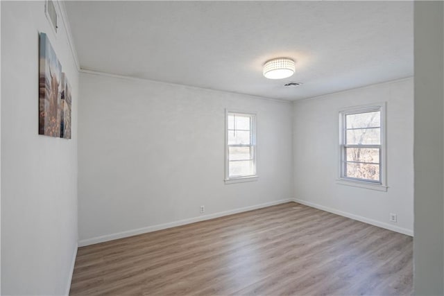 spare room featuring baseboards, visible vents, and light wood-style floors