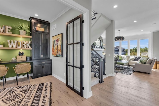 bar featuring ornamental molding, baseboards, light wood finished floors, and stairs