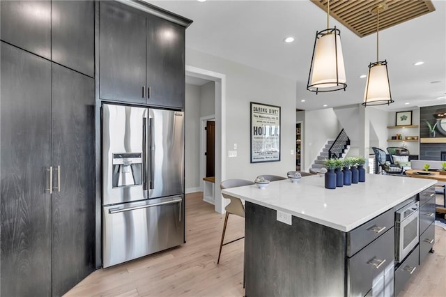 kitchen with a kitchen island, appliances with stainless steel finishes, open floor plan, a breakfast bar area, and hanging light fixtures