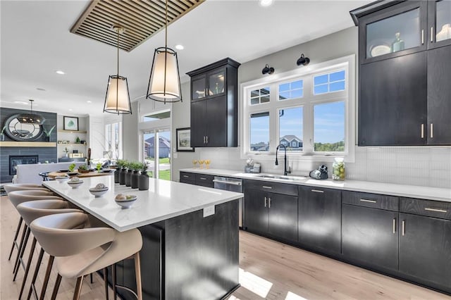 kitchen with glass insert cabinets, open floor plan, decorative light fixtures, a center island, and a sink